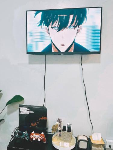a television hanging on a wall with a desk with at Cozy Staycation with Netflix, Pool, PS4, Board Games in Manila