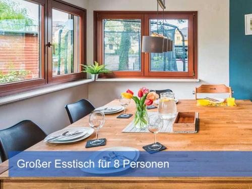 a wooden table with chairs and a vase of flowers at Ideal für Kinder - Familientreffen - Ferienhaus Elbharmonie - Hunde herzlich willkommen in Dresden