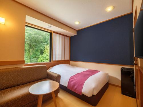 a bedroom with a bed and a couch and a window at Mizunoto Reopening on April 1, 2025 in Hakone