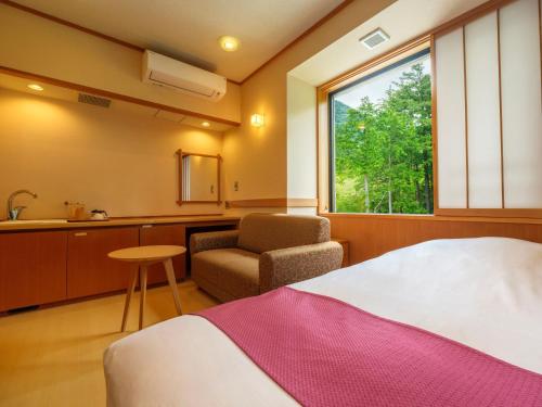 a bedroom with a bed and a chair and a window at Mizunoto Reopening on April 1, 2025 in Hakone