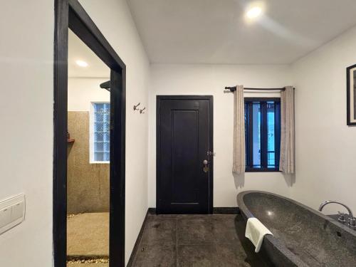 a bathroom with a large tub and a black door at The Bliss Angkor in Siem Reap