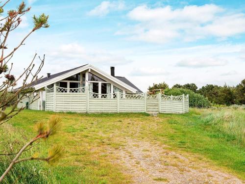 a house on a hill with a white fence at 4 star holiday home in Rømø in Bolilmark