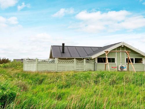 a green house with a black roof in a field at 4 star holiday home in Rømø in Bolilmark