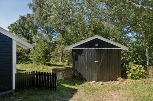 a wooden shed in a yard next to a fence at Experience Nature's Embrace And Peace in Græsted