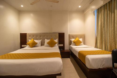 two beds in a hotel room with yellow pillows at Hotel Malad Inn opposite Malad Railway Station in Mumbai
