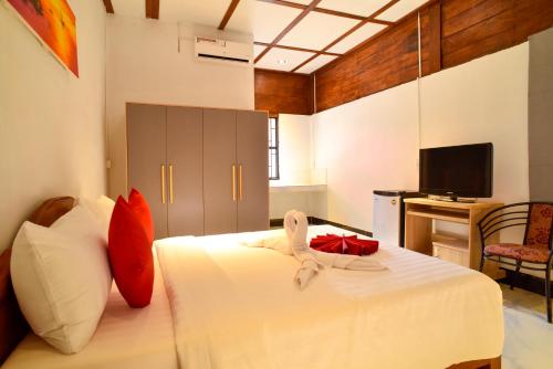 a bedroom with a bed with white sheets and red pillows at Studio Ground Floor Room by Densy Angkor in Siem Reap
