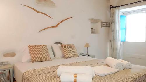 a white bedroom with two beds and a window at Paros Heritage Retreat by ΜΡS in Parikia