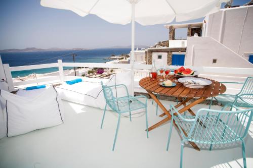 a table and chairs on a balcony with the ocean at Mykonos Moussa in Agios Ioannis Mykonos