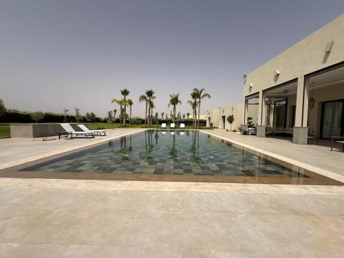 a swimming pool in front of a building with palm trees at Luxury Villa Pool with Atlas View in Moussiha