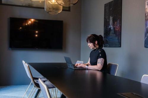 a woman sitting at a table with a laptop at Citybox Antwerp in Antwerp