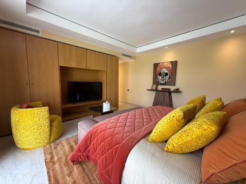a bedroom with a bed with yellow pillows and a television at Luxury Villa Pool with Atlas View in Moussiha