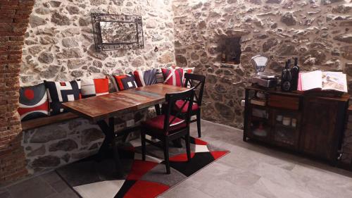a table and chairs in a room with a stone wall at LA TANA DELLA VOLPETTA - Bed & Breakfast in Stella