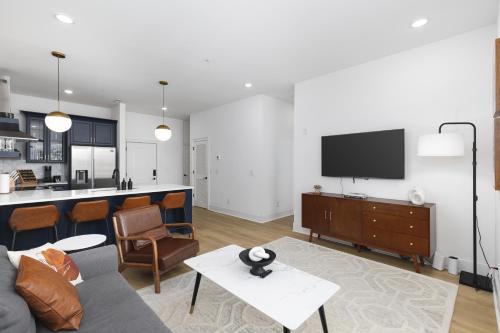 a living room with a couch and a tv on a wall at Hip New Condo near Broadway and Trendy East Nash with 5 Beds in Nashville