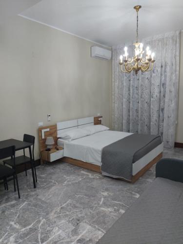 a bedroom with a bed and a table and a chandelier at Arte Mia suite in Reggio Calabria