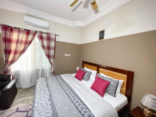 a bedroom with a bed with pink pillows and a window at Eden Vale Hotel in Ajiringano