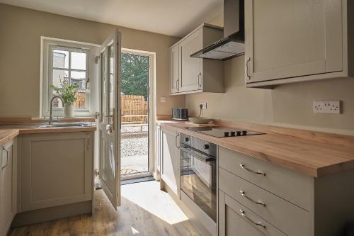 eine Küche mit weißen Schränken und einer offenen Tür in der Unterkunft 1 Manor Cottage, Ainderby Steeple, DL7 9PX in Northallerton