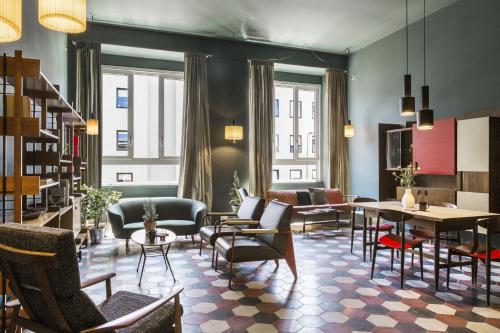 a lobby with chairs and tables and a library at casaBASE in Milan