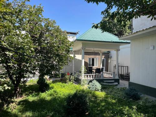 una pequeña casa blanca con techo verde en Timurbek Hotel OK, en Aktepa-Chigatay