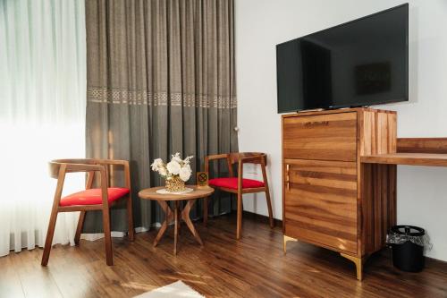 a hotel room with a tv and two chairs and a table at Edemus - Motel & Restaurant in Maglaj