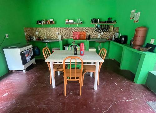 a kitchen with a table and chairs and green walls at Quarto para 6 a 900m da Vila do Capão in Vale do Capao