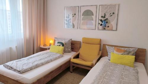 Habitación con 2 camas y silla amarilla en Apartment E - feel good, en Leipzig
