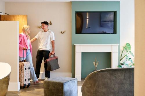 a man and woman walking through a living room with a fireplace at Fairlawns, Hotel And Spa in Walsall