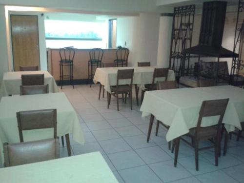un comedor con mesas y sillas blancas en Hotel Milena en Mendoza