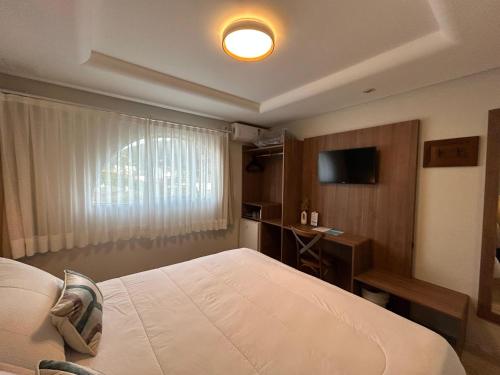 a bedroom with a bed and a desk and a television at Hotel VillaReal Guaratuba - Caieiras in Guaratuba