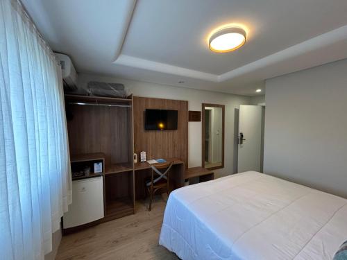 a bedroom with a bed and a desk with a computer at Hotel VillaReal Guaratuba - Caieiras in Guaratuba
