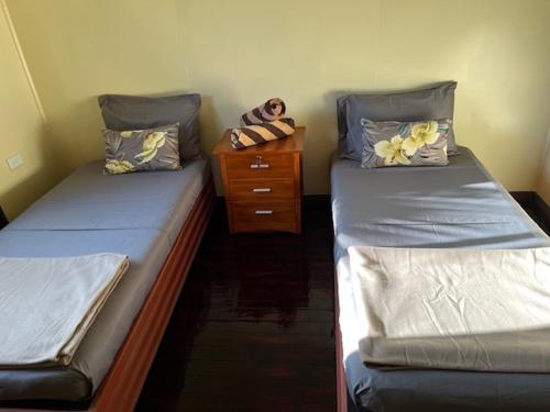 two twin beds in a room with a dresser at Vale Kau in Nadi
