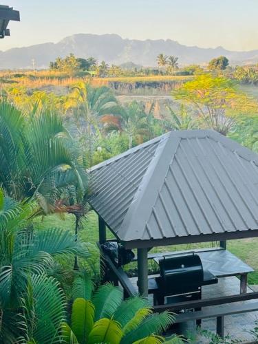 a bench with a metal roof in a field at Vale Kau in Nadi
