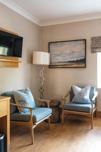 a living room with two chairs and a tv at Fairlawns, Hotel And Spa in Walsall