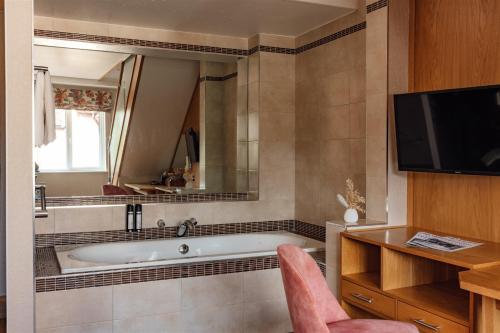 a bathroom with a bath tub and a tv at Fairlawns, Hotel And Spa in Walsall