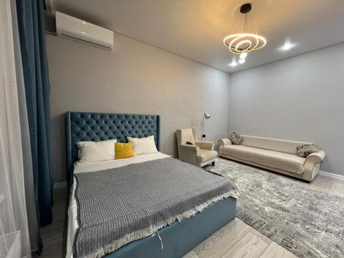 a bedroom with a bed and a couch at Respublika LUX Уютная 2-комнатная квартира in Astana