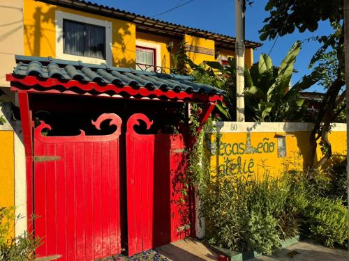 a red gate in front of a yellow house at Pousada Leão in Maceió