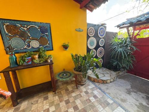 a room with a yellow wall with a table and plants at Pousada Leão in Maceió