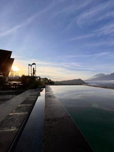 a pool of water with the sunset in the background at Pinggan Campside Glamping in Baturaja