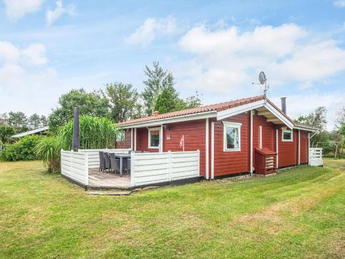 une maison rouge avec une clôture blanche dans une cour dans l'établissement 6 person holiday home in Glesborg-By Traum, à Fjellerup