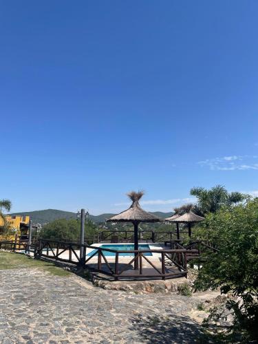 a picnic table with umbrellas and a swimming pool at Cabañas Terrazas del Sol in Villa Carlos Paz