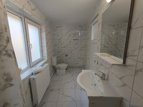 a white bathroom with a sink and a toilet at Casa Ioana Întorsura Buzăului in Brădet