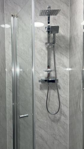 a shower with a shower head and a shower at QueensBerry Hotel in Annan