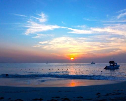 a boat in the ocean with a sunset in the background at DNA Studio in Potters Village