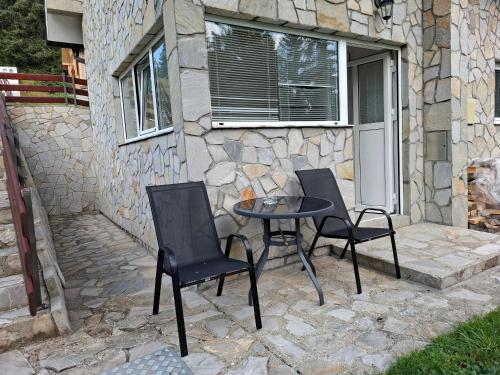 two chairs and a table on a stone patio at Tvoja kućica za beg 2 in Plešin