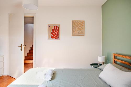 a white bedroom with a bed and two pictures on the wall at Piazza San Giacomo - Attico su due livelli in Udine