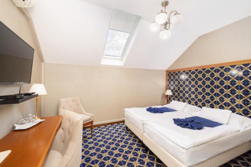 a bedroom with a bed and a desk and a tv at Hotel Central in Nyíregyháza