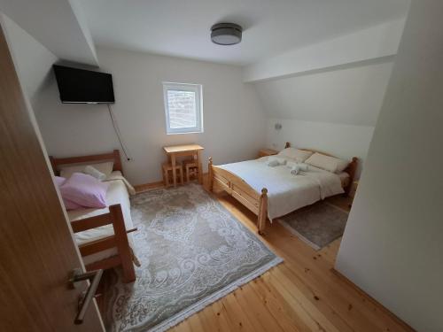 a small bedroom with two beds and a television at Tvoja kućica za beg 2 in Plešin