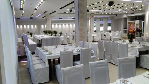 une salle à manger avec des tables et des chaises blanches dans l'établissement Svadbeni salon STEFAN, à Nevesinje