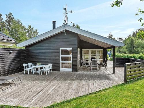 a house with a deck with a table and chairs at 4 star holiday home in Ålbæk in Ålbæk