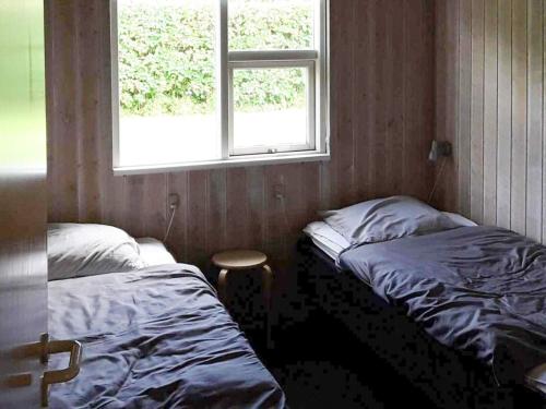 two beds in a room with a window and a stool at Modern Retreat with Spa - By Traum Ferienwohnungen in Nordborg