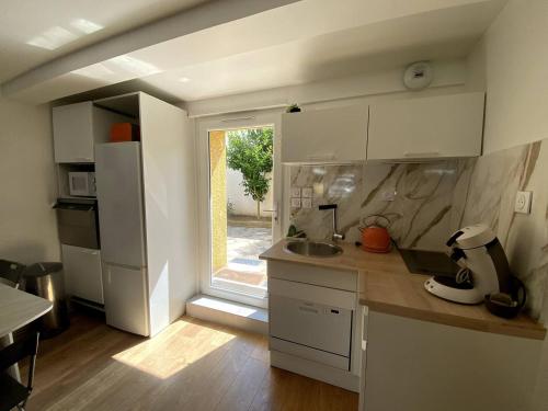 a kitchen with white cabinets and a sink and a window at Maison climatisée Lyon-Bron Eurexpo - Stadium Groupama - Interdit aux événements in Bron